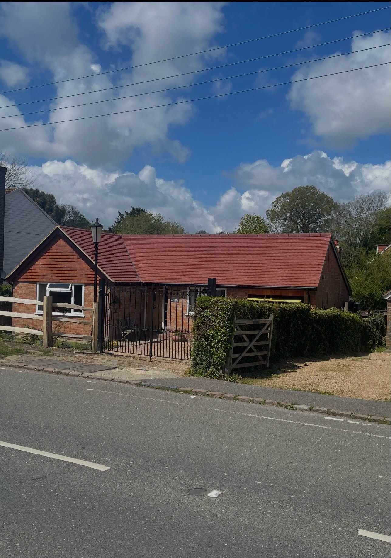Bungalow with a red tiled roof behind a hedge