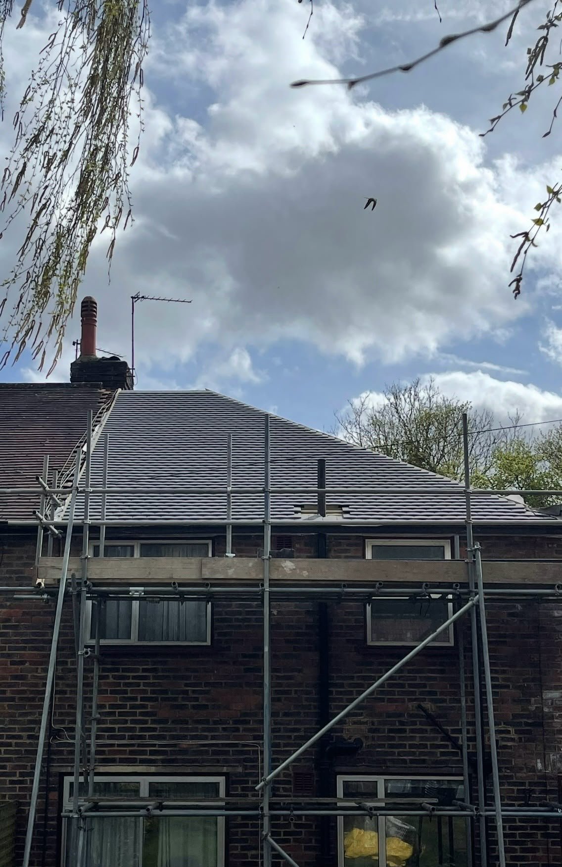 Dark tiled roof with scaffolding along the front of the house